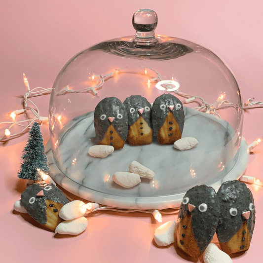 Black sesame penguin madeleines surrounded by holiday decorations.