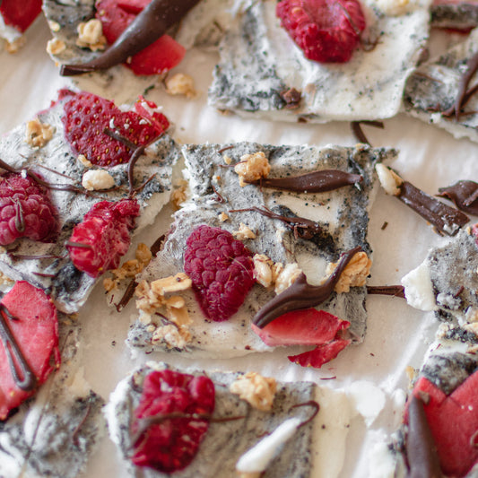 Close-up shot of Rooted Fare's Black Sesame Crunchy Butter marbled into yogurt, frozen, and topped with raspberries, strawberries, and dark chocolate drizzle.