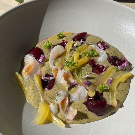 Black Sesame Sabayon -- a beautifully colorful dish within a grey stone-texture bowl. Base is yellow with flecks of black, topped with white lychee, dark cherries and raspberries, and more.