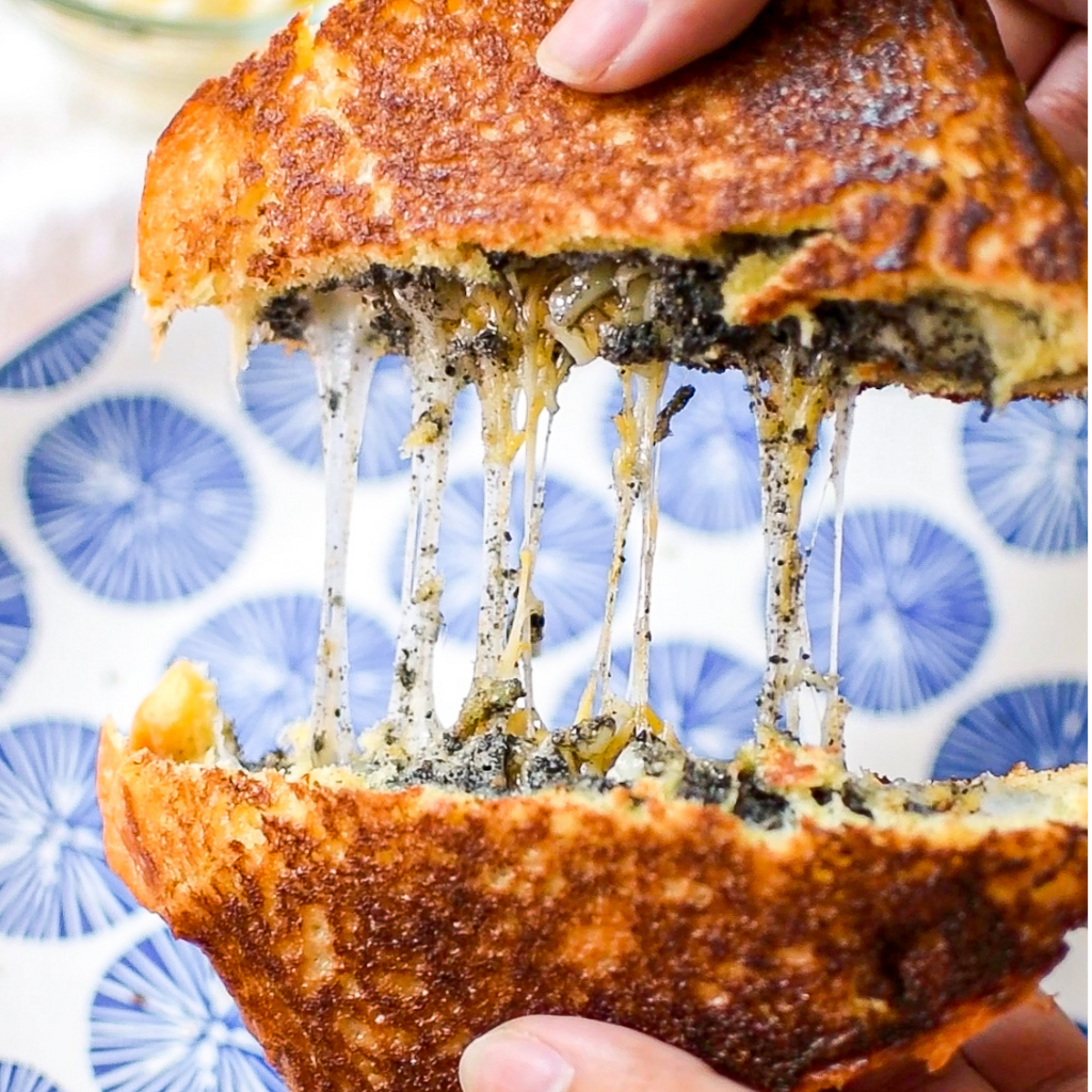 A grilled cheese sandwich being pulled apart, revealing the cheesy and black sesame-y inside.