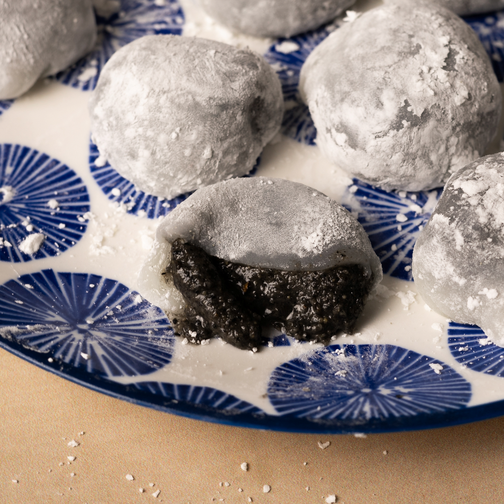 A ripped open powdered mochi with the luscious Crunchy Black Sesame Butter center showing.