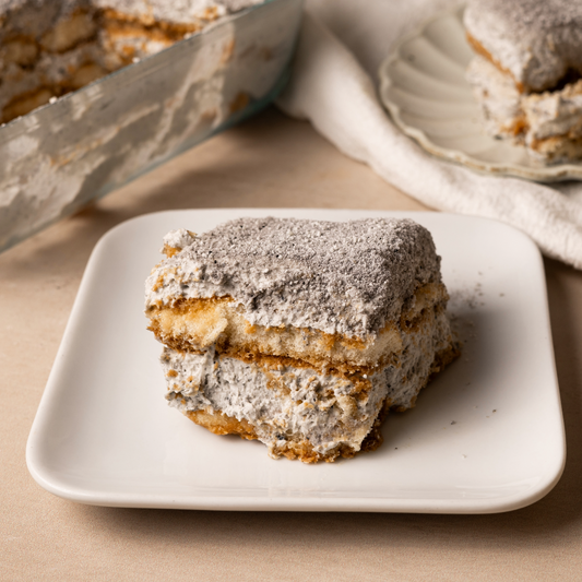 A slice of layered tiramisu on a square white plate.