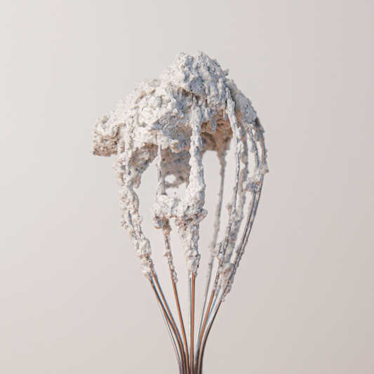 Speckled black sesame whipped cream on a whisk.